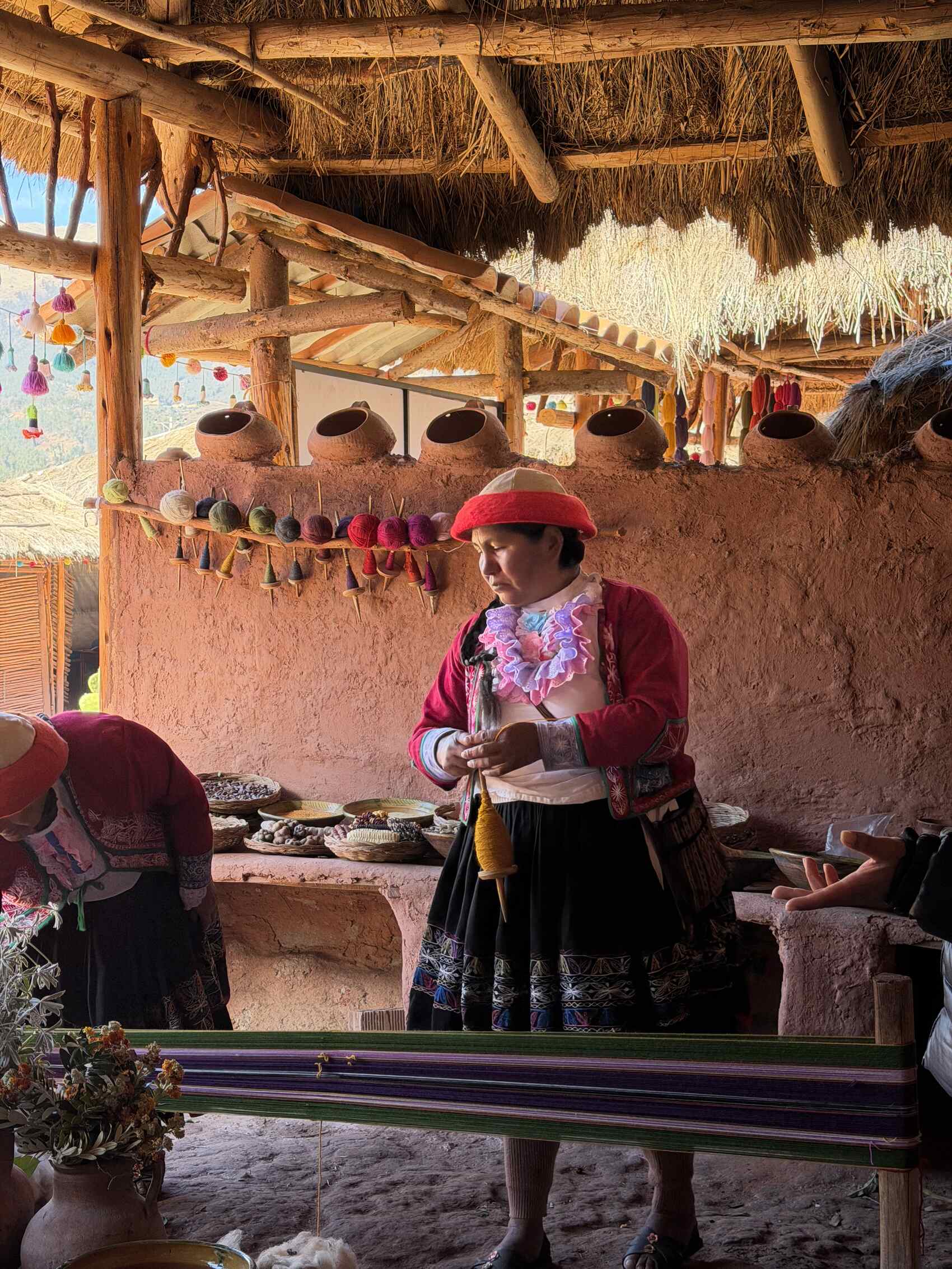 A local woman from the Indigenous Quechua community weaving with alpaca wool