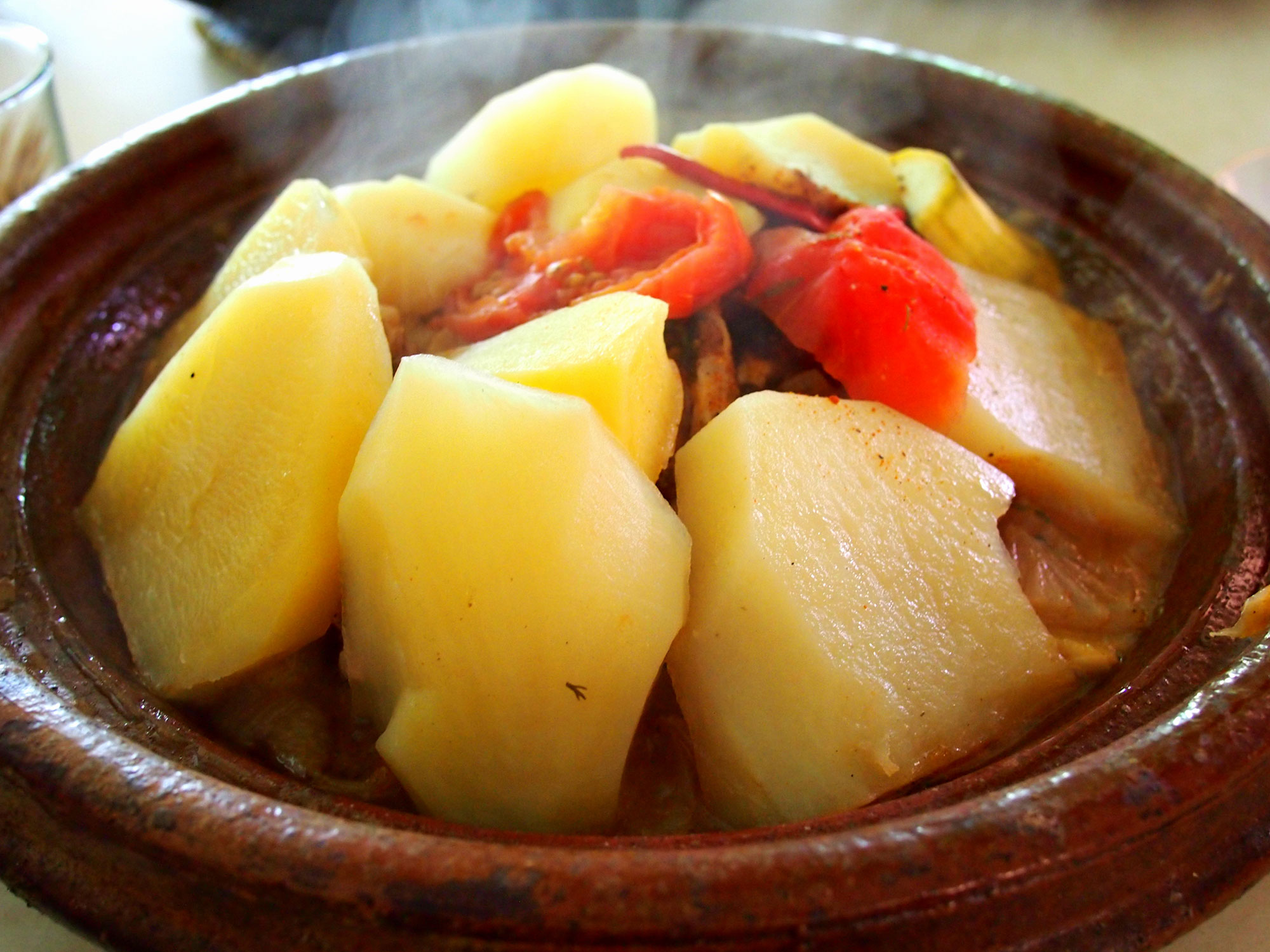 Potatoes cover up the meat and vegetables below in this chicken tagine from Morocco.