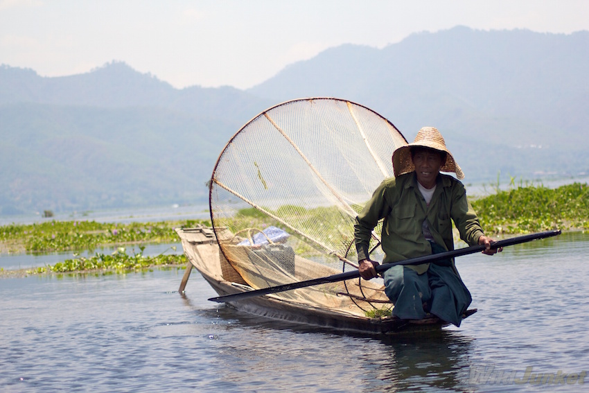 A fisherman with a large conical-shaped fish trap.