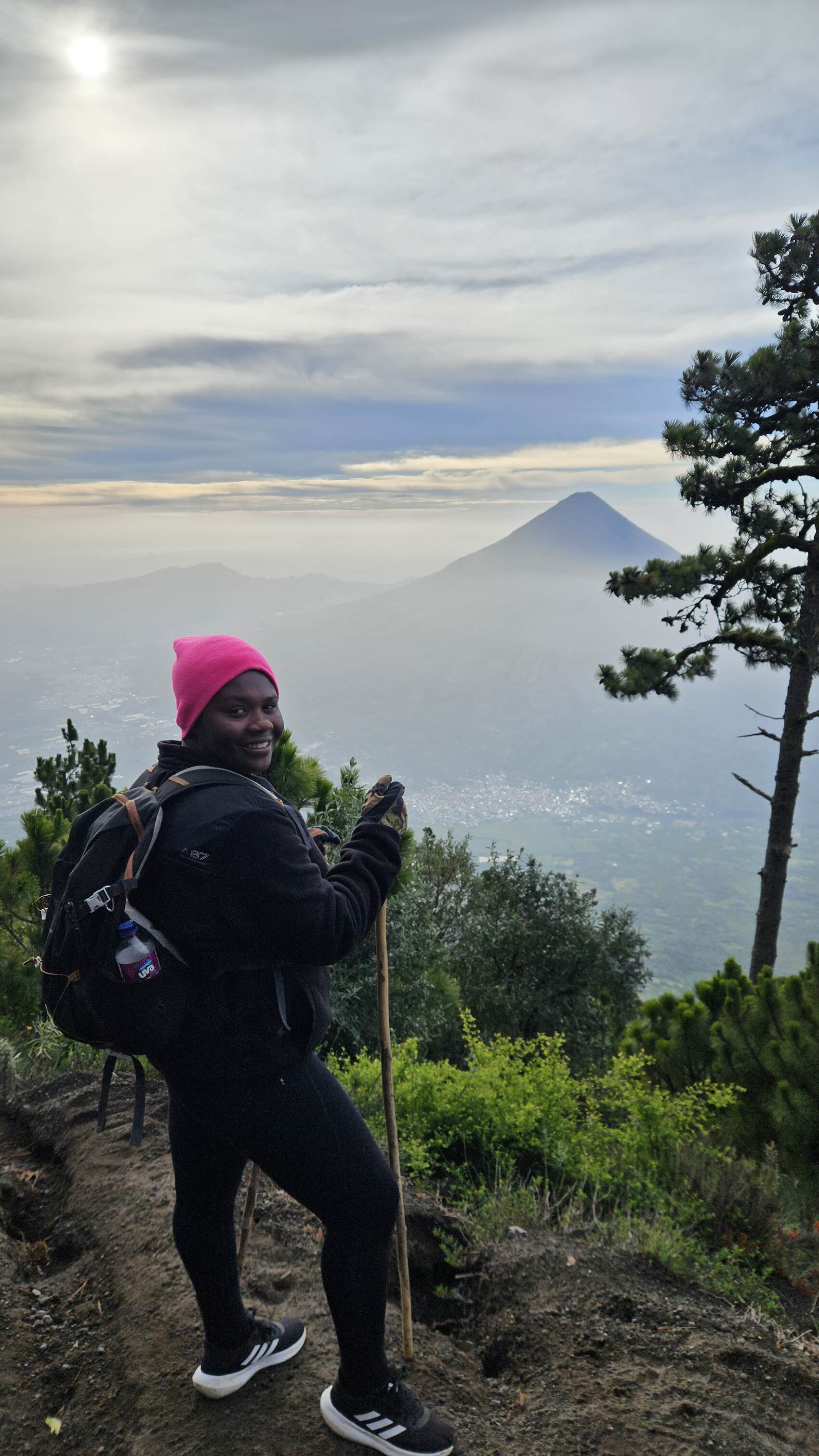 Ivy posing for a photograph in front of a volcano in Southeast Asia wearing a colourful hat