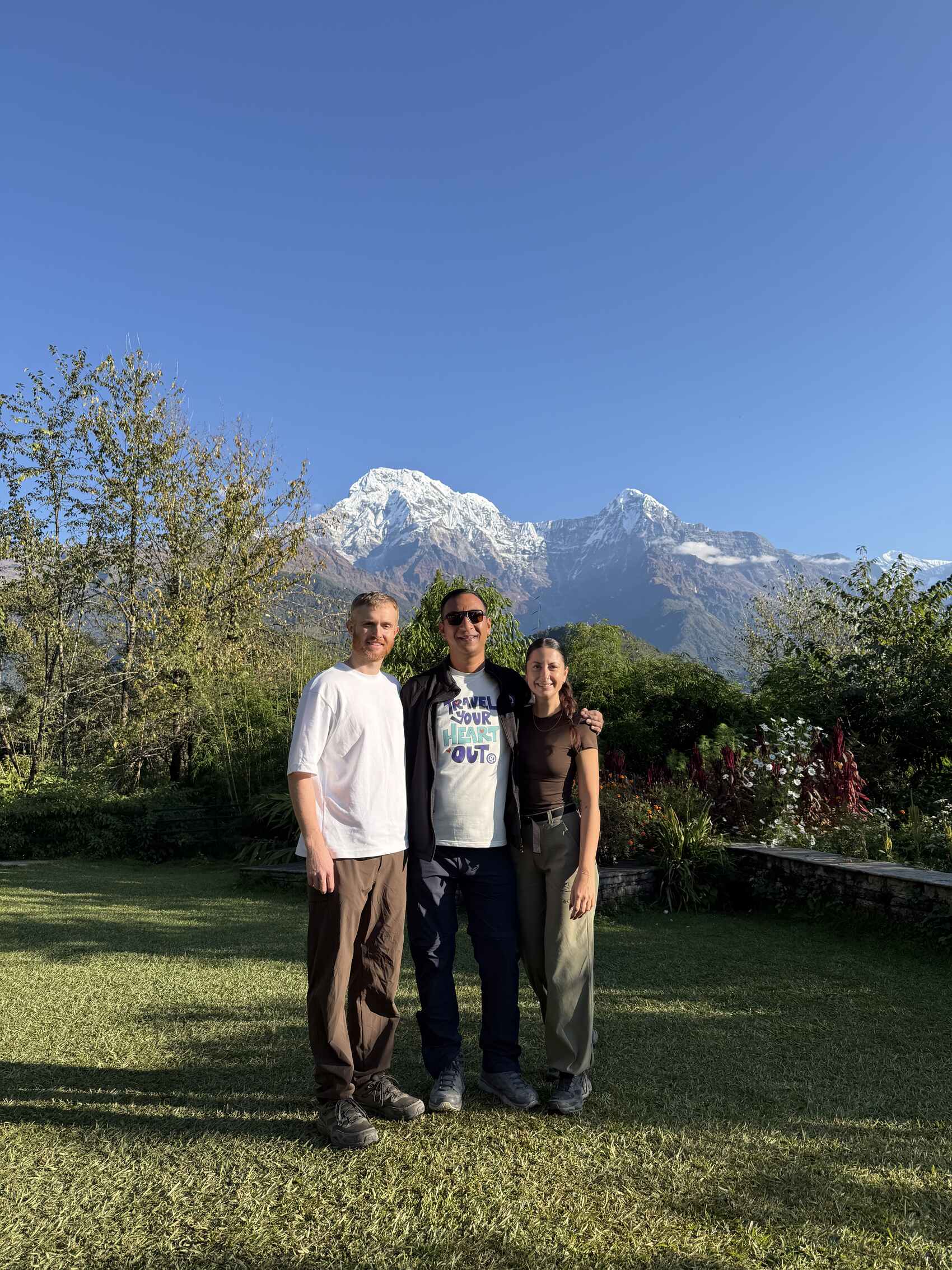 Raeann Watt, Mike Turnbull, and their CEO standing in front of the towering peak of Annapurna in Nepal