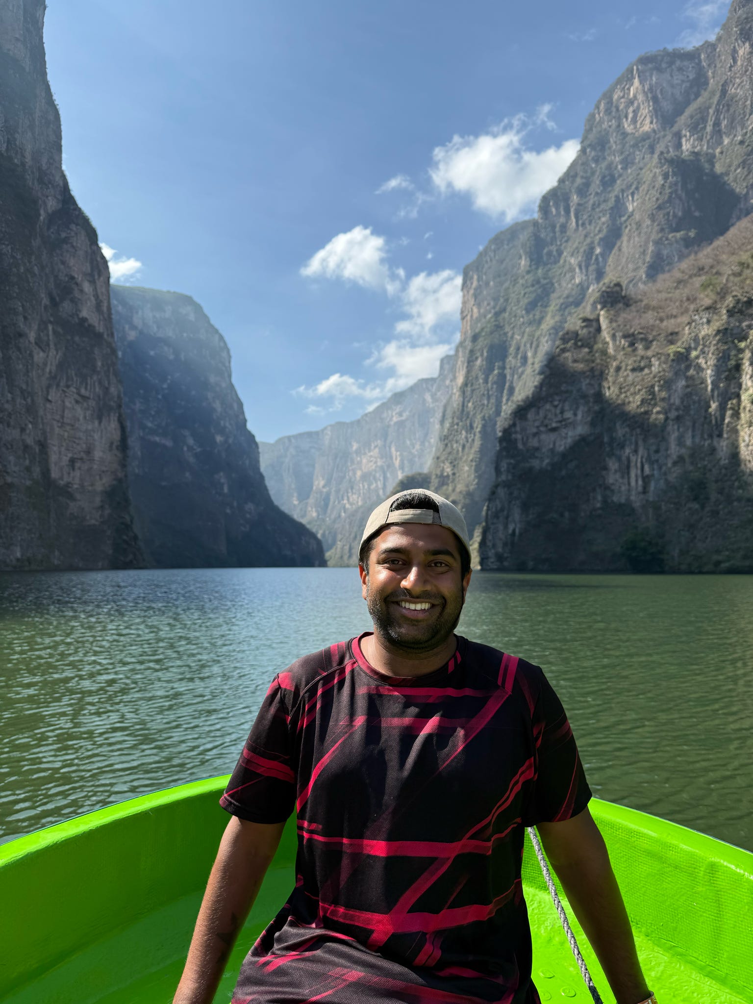 Ritesh Maharaj posing for a picture in front of towering cliffs in South America