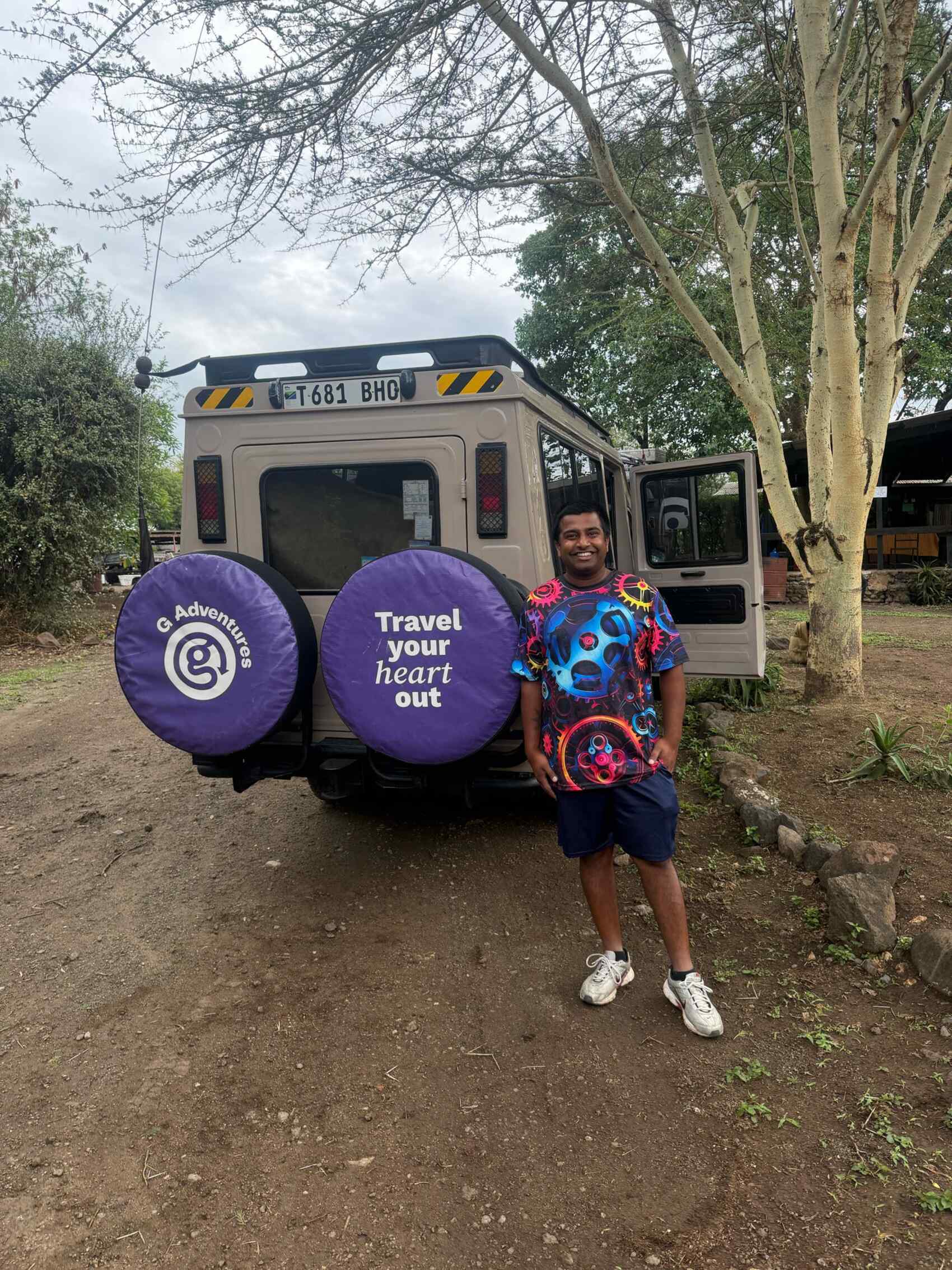 Ritesh Maharaj posing for a picture in front of a G Adventures safari vehicle
