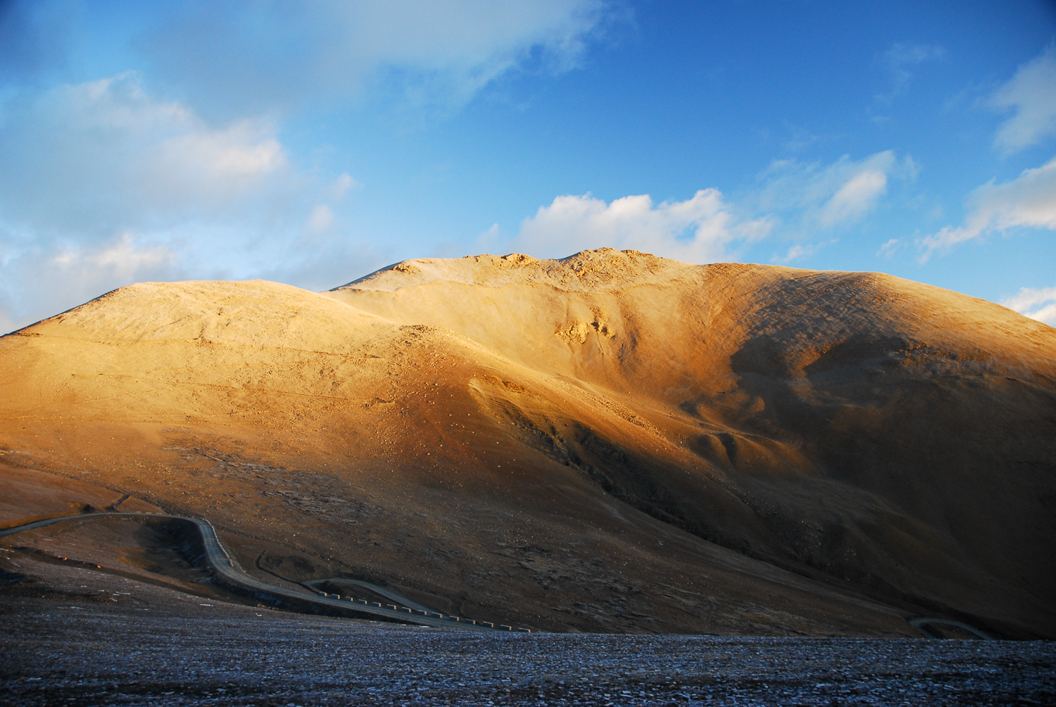 The arid and brown landscape of the Tibetan Plateau sits in stark contrast to the blue skies above it.